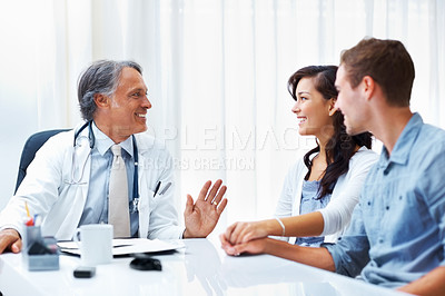 Buy stock photo Portrait of happy couple conversing with experienced mature doctor in clinic