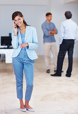 Buy stock photo Full length of successful young woman on call with business people discussing in background