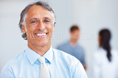 Buy stock photo Closeup of handsome mature man smiling with associates in background