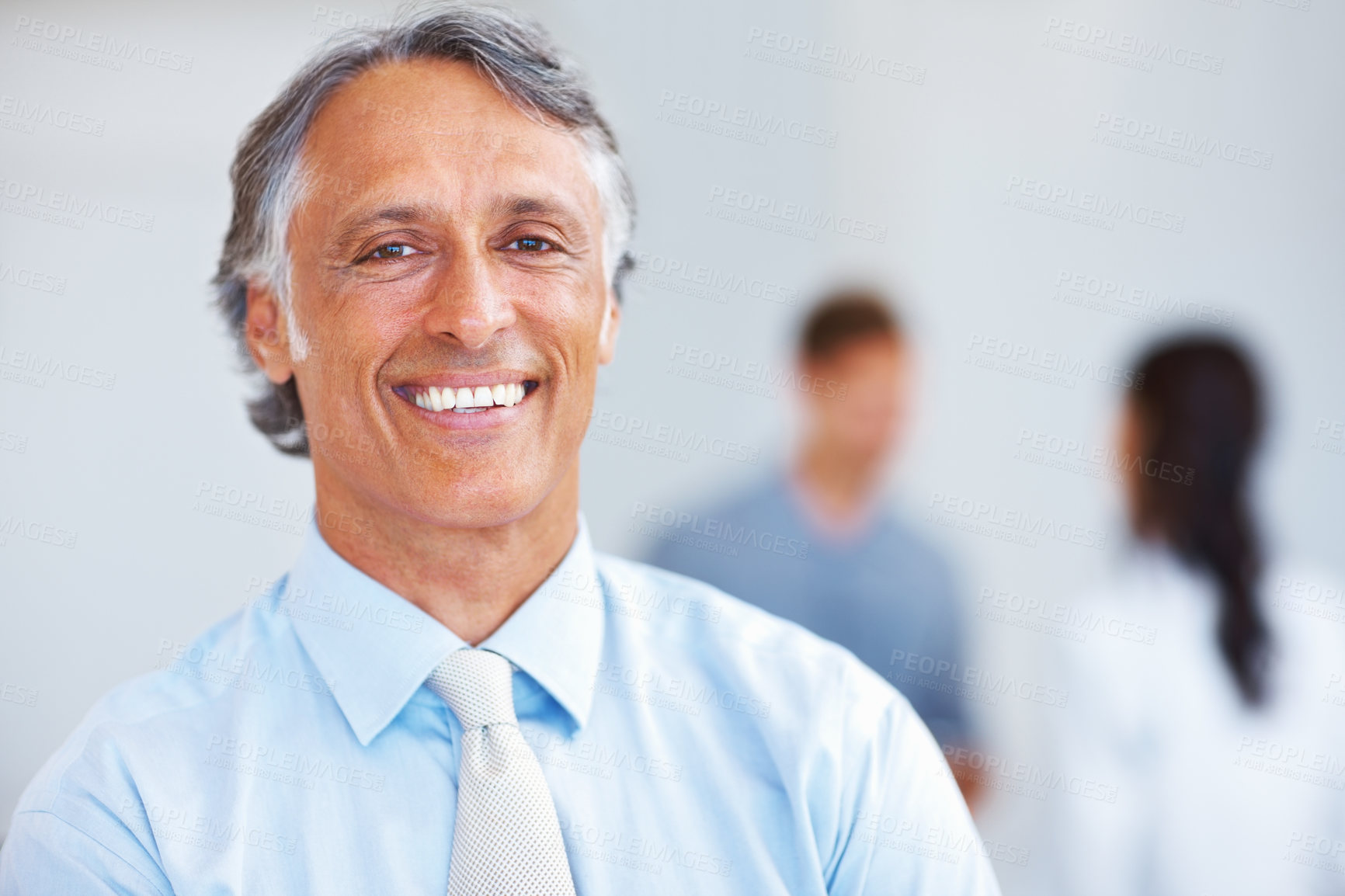 Buy stock photo Closeup of handsome mature man smiling with associates in background