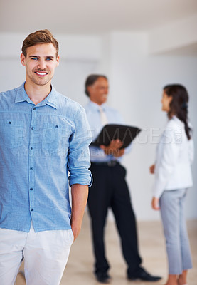 Buy stock photo Young corporate looking man standing with colleagues in background