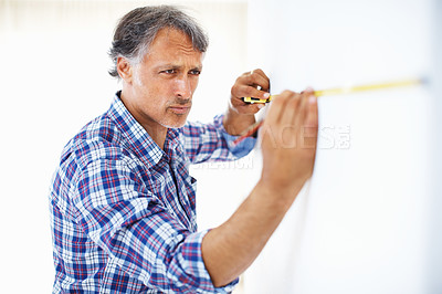 Buy stock photo Mature engineer measuring wall with masking tape