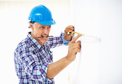 Buy stock photo Mature engineer in hardhat taking measurement on the wall