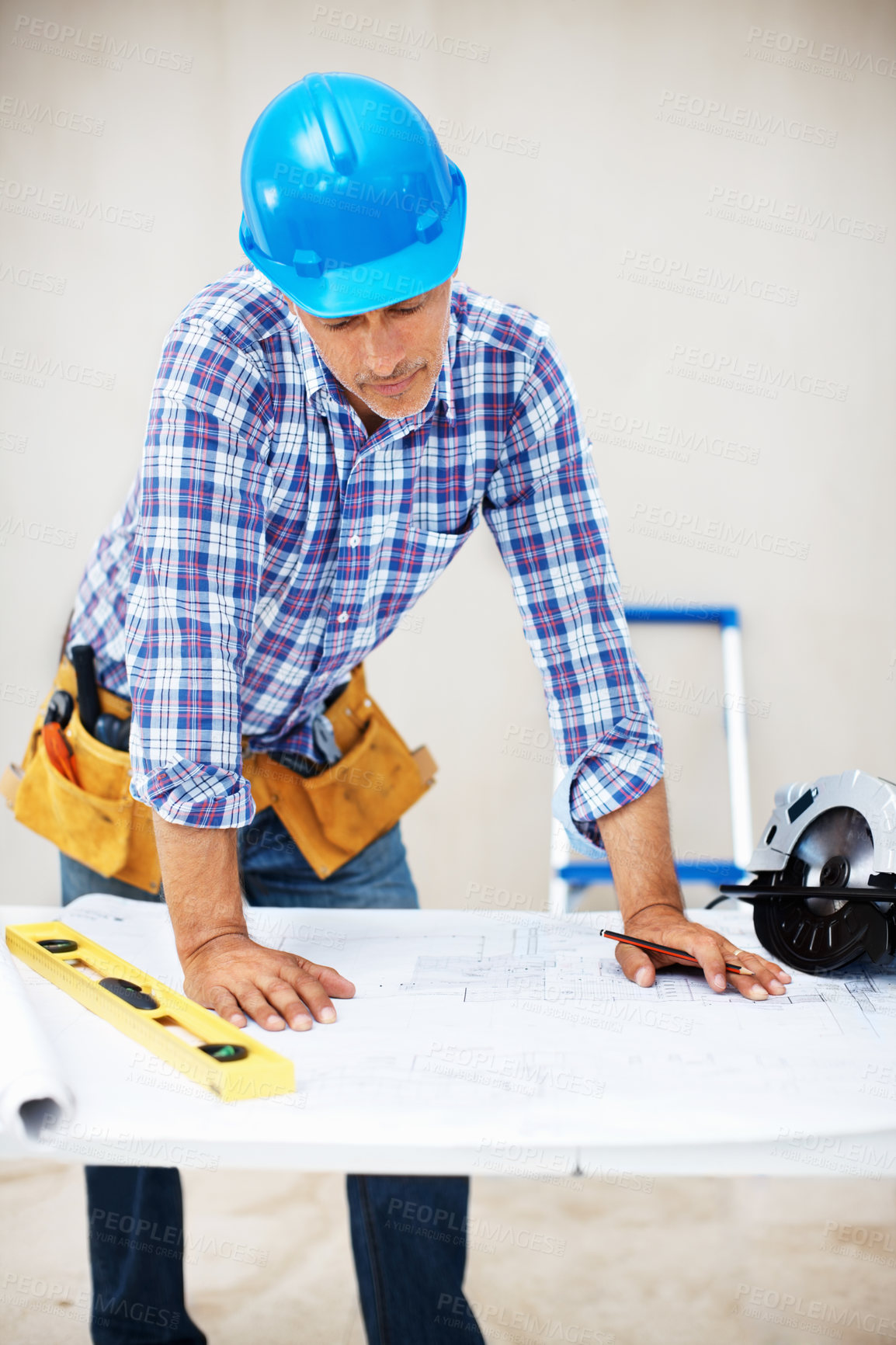 Buy stock photo Mature engineer in hardhat looking at blueprint