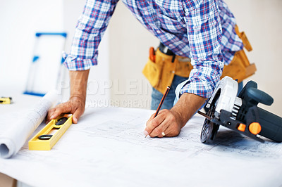 Buy stock photo Closeup of busy architect working on blueprint using level and pencil