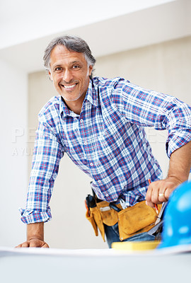 Buy stock photo Mature engineer smiling while working on blue print