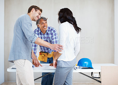 Buy stock photo Happy couple discussing home renovation plan with architect while looking at blueprint