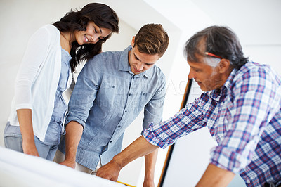 Buy stock photo Attractive young woman and man discussing home renovation plan with architect