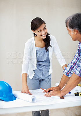 Buy stock photo Young woman smiling while discussing home renovation plan with architect