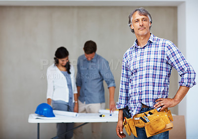 Buy stock photo Portrait of confident mature architect with couple examining blueprint in background