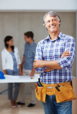Buy stock photo Portrait of mature architect smiling with hands folded while clients discussing in background