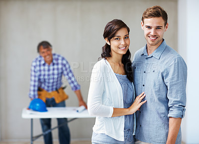 Buy stock photo Portrait of attractive young couple smiling with architect in background