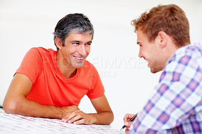 Buy stock photo Two smiling photographers sitting together at table and discussing