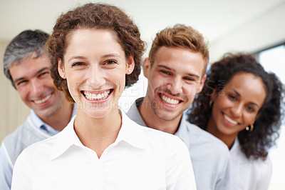 Buy stock photo Closeup portrait of a positive-looking young professional with her coworkers standing behind her