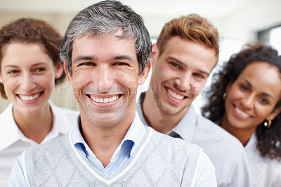 Buy stock photo Closeup portrait of a positive-looking professional with his coworkers standing behind him