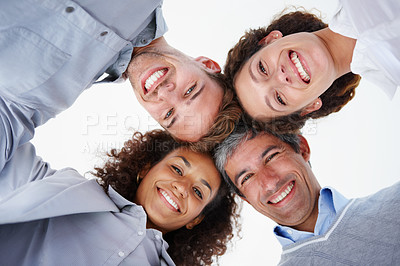 Buy stock photo Low angle portrait of a group of positive-looking businesspeople standing arm in arm in a huddle