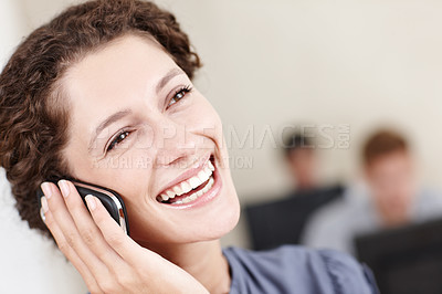 Buy stock photo Closeup portrait of a smiling young businesswoman talking on the phone with her colleagues sitting in the background