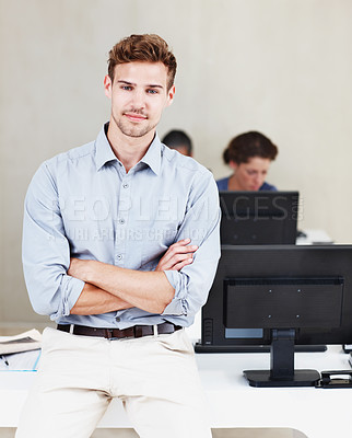 Buy stock photo Portrait of a confident young office worker with his colleagues working on computers in the background