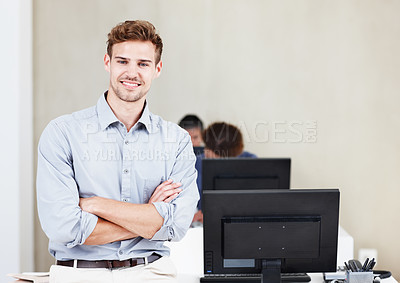 Buy stock photo Portrait of a positive-looking young office worker with his colleagues working on computers in the background