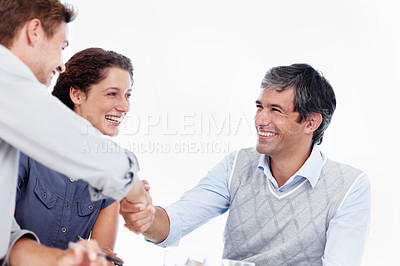 Buy stock photo Shot of two businessmen shaking hands while in a meeting with a female coworker