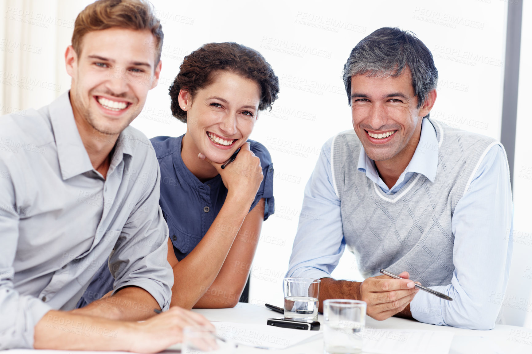Buy stock photo Portrait of three confident looking businesspeople sitting at a table