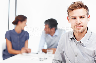 Buy stock photo Closeup portrait of a confident young businessman with his colleagues sitting in the background
