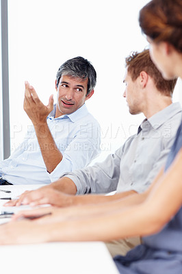 Buy stock photo Shot of three positive-looking businesspeople talking together in a meeting