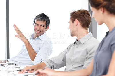 Buy stock photo Shot of three positive-looking businesspeople talking together in a meeting