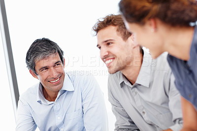 Buy stock photo Shot of three positive-looking businesspeople talking together in a meeting