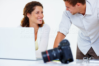 Buy stock photo Male and female executives using laptop and looking at each other with camera in foreground