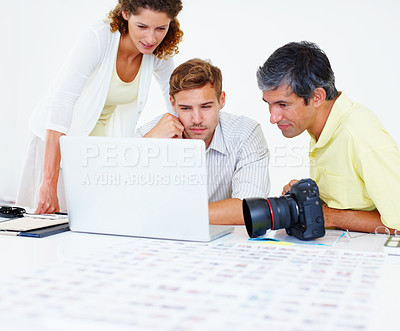 Buy stock photo Three professional photographers working on laptop and looking at the screen