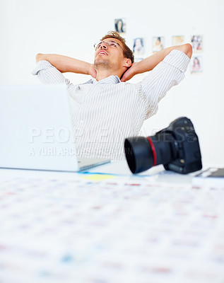 Buy stock photo Photographer using laptop and relaxing with hands behind head