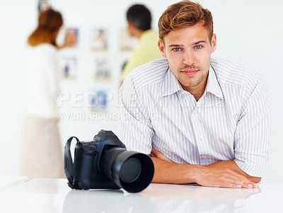 Buy stock photo Portrait of photographer sitting at table with people looking at pictures in background