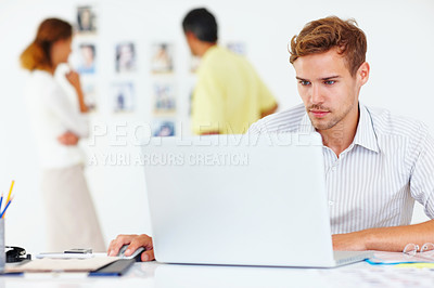 Buy stock photo Male photographer using laptop with people looking at pictures in background
