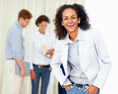 Buy stock photo Beautiful business woman with hands in pockets and colleagues discussing in background