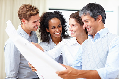 Buy stock photo Group of business people in discussion with blueprint