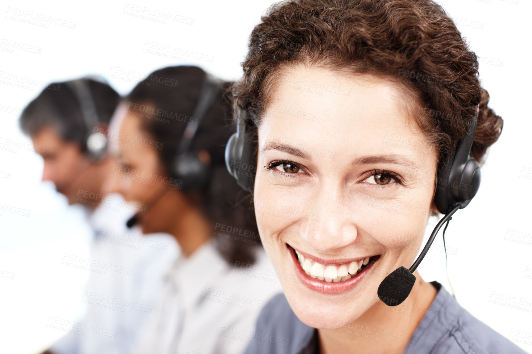 Buy stock photo Closeup portrait of a smiling call center professional with colleagues seated in the background