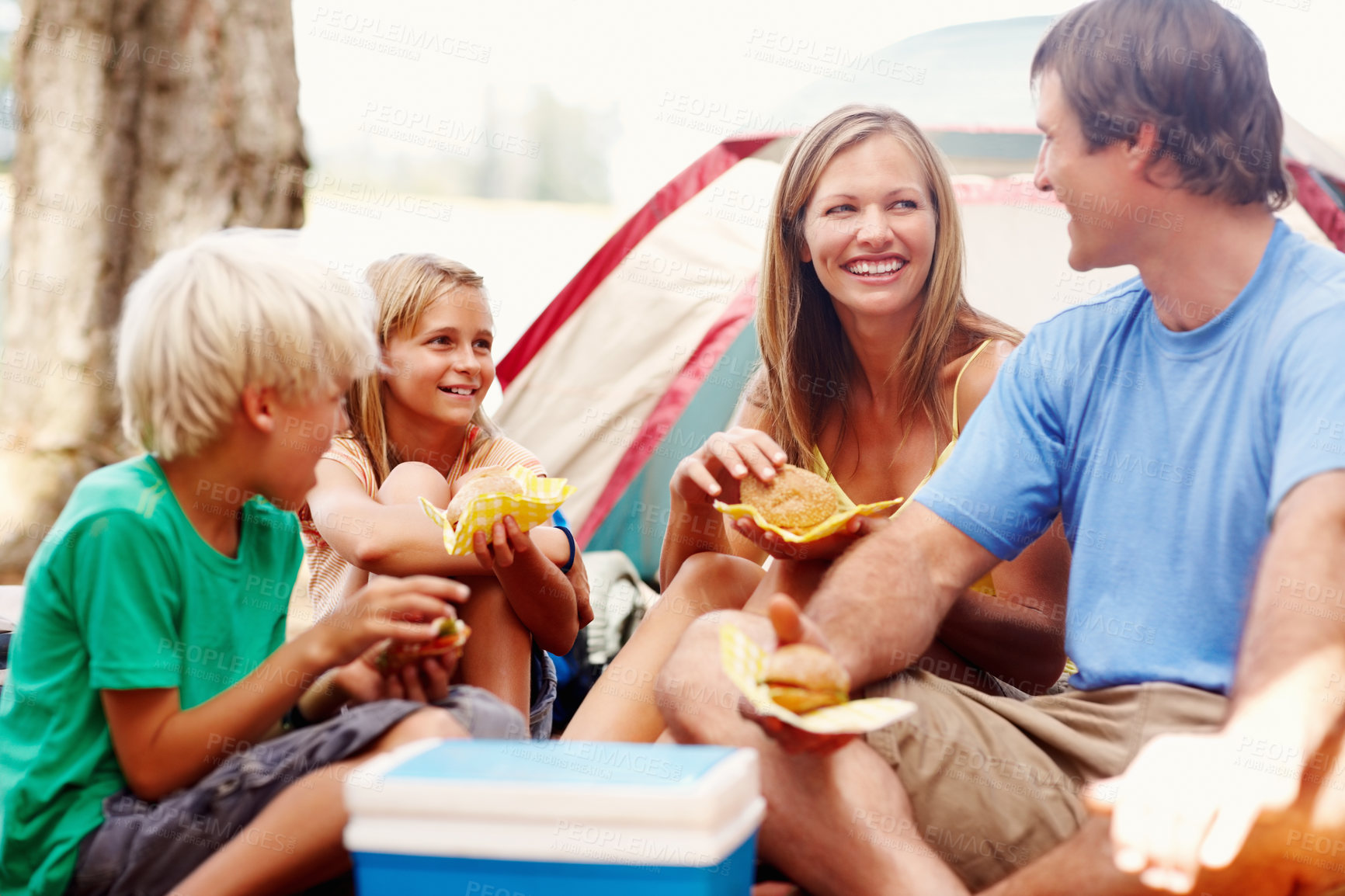 Buy stock photo Happy, parents and children at campsite, eating and bonding with food in woods, love and adventure in forest. Nature, dad and mom with smile, tent and fun of camping, woman and laughing with kids