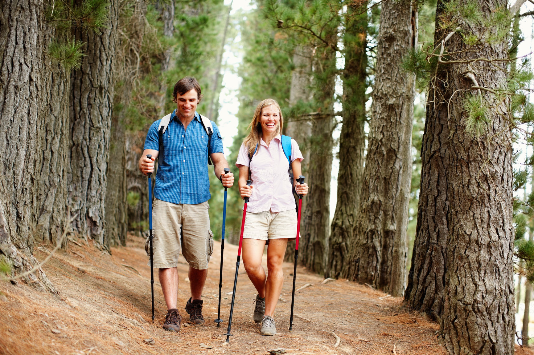 Buy stock photo Walking, couple and hiking in forest, smile and adventure for vacation, man and woman with backpack. Outdoor, fun and people with trekking poles, travel and woods with rough terrain in New Zealand