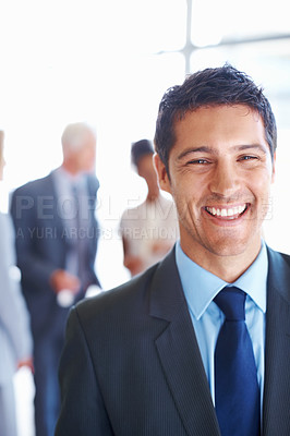 Buy stock photo Portrait of handsome business man smiling with associates discussing in background