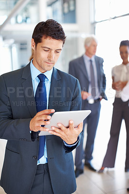 Buy stock photo Portrait of handsome business man using electronic tablet with executives in background