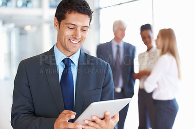 Buy stock photo Portrait of smart young business man using electronic tablet with executives in background