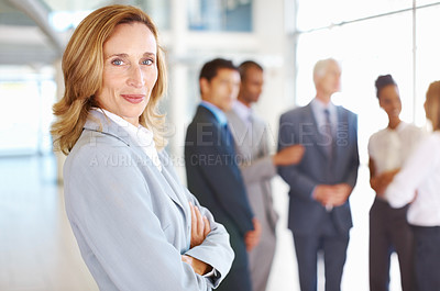 Buy stock photo Portrait of confident mature business woman with team conversing in background