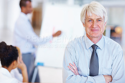 Buy stock photo Portrait of smiling senior business man with executives in background at office
