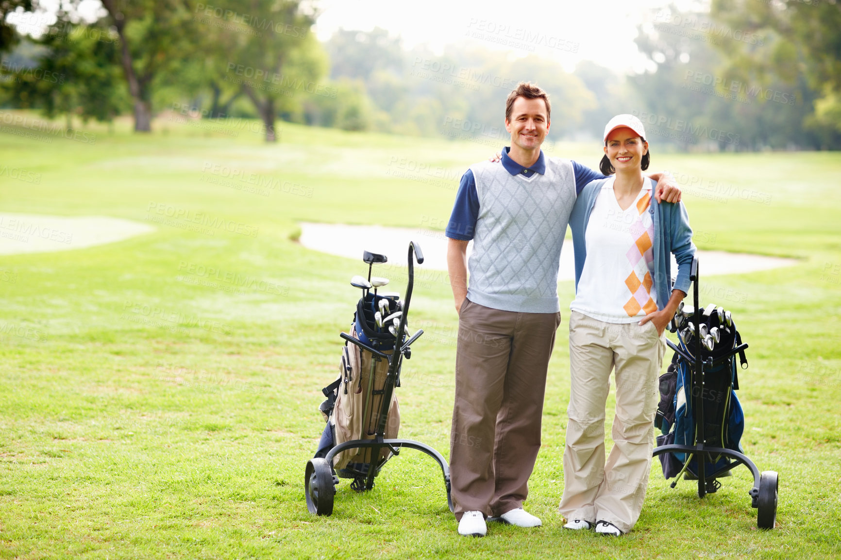 Buy stock photo Full length of happy golfing couple with arms around and smiling