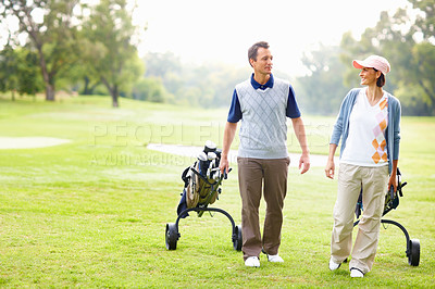 Buy stock photo Full length of an attractive couple walking with golf bags