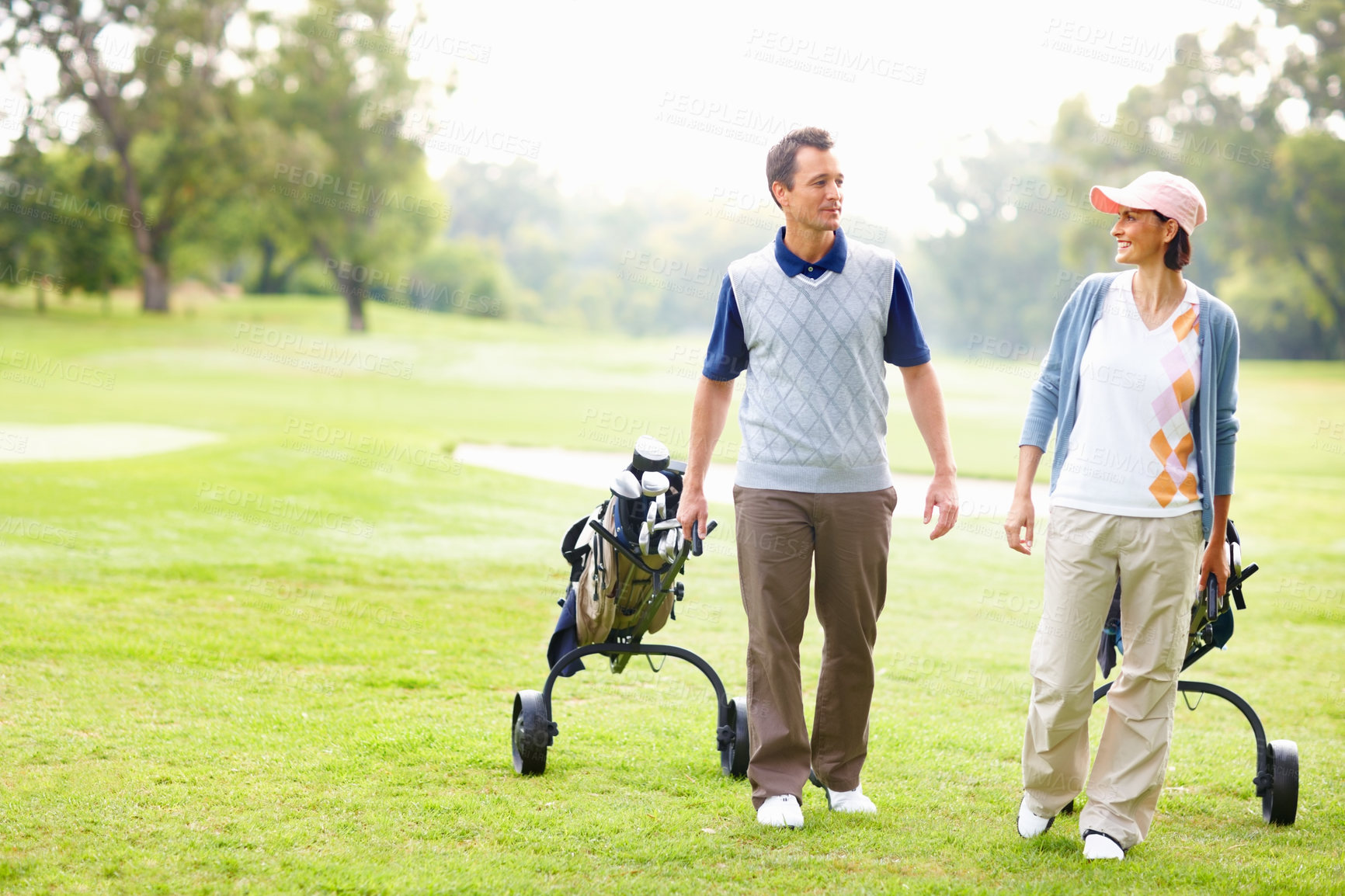 Buy stock photo Full length of an attractive couple walking with golf bags