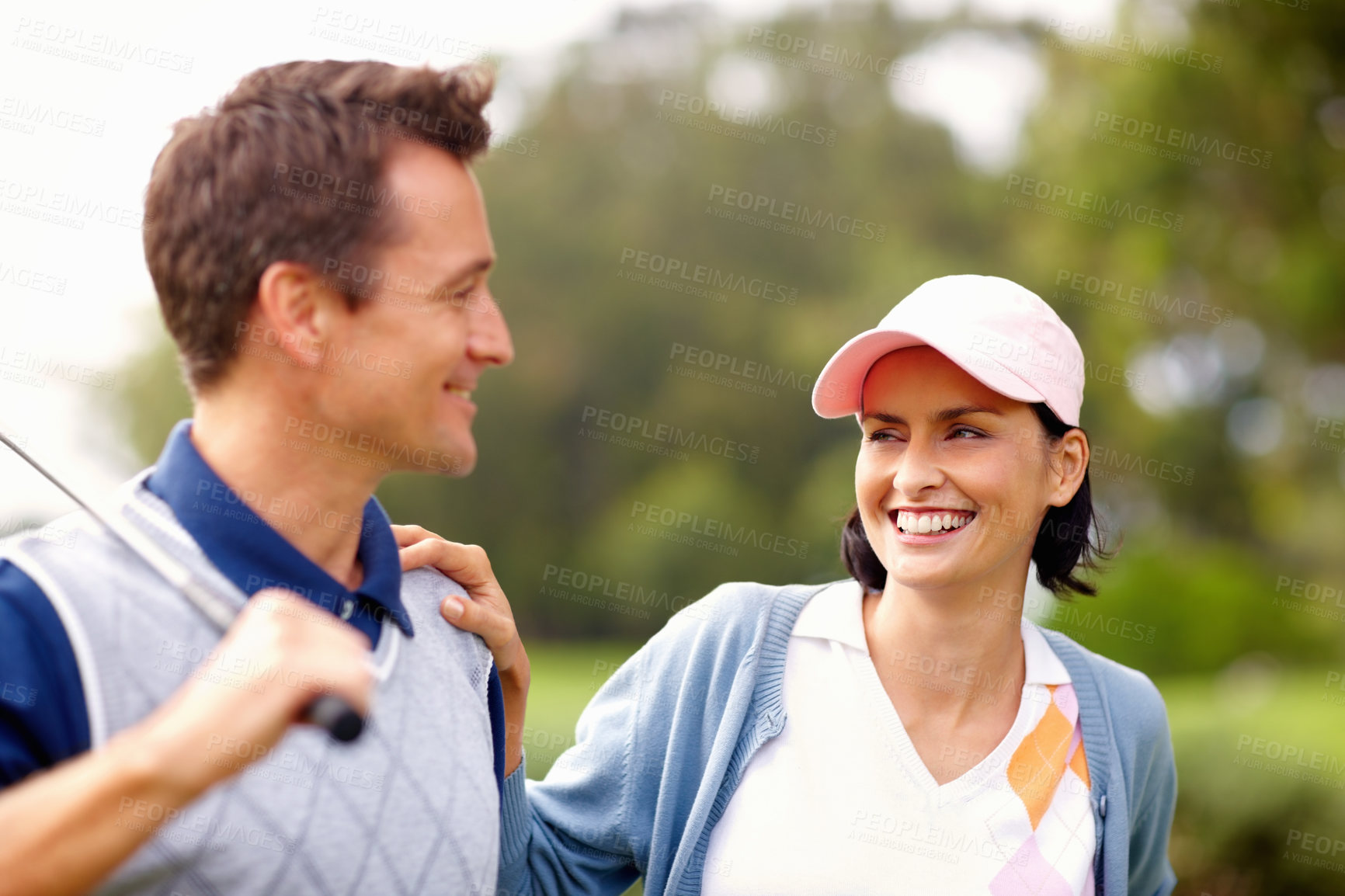 Buy stock photo Attractive golfing couple smiling and looking at each other
