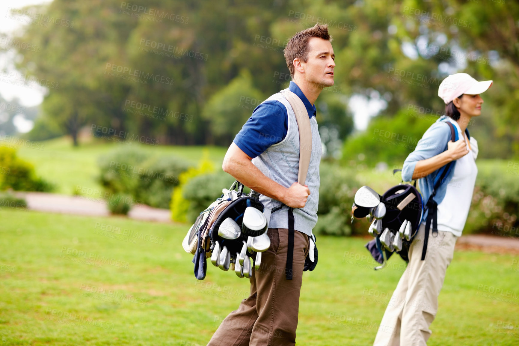 Buy stock photo Man and woman walking with golf bags and looking away