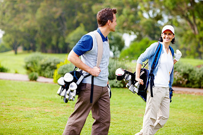 Buy stock photo Couple carrying golf bags and looking at each other